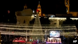 Palestinian Christians celebrate the lighting of a Christmas tree outside the Church of the Nativity, traditionally believed by Christians to be the birthplace of Jesus Christ in the West Bank city of Bethlehem, Saturday, Nov. 30, 2019. (AP Photo/Majdi Mo
