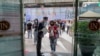 A woman displays her phone to doorman, to confirm using a mobile application to help contact-tracing at the entrance to the upmarket shopping mall Siam Paragon in Bangkok, Thailand, May 17, 2020.