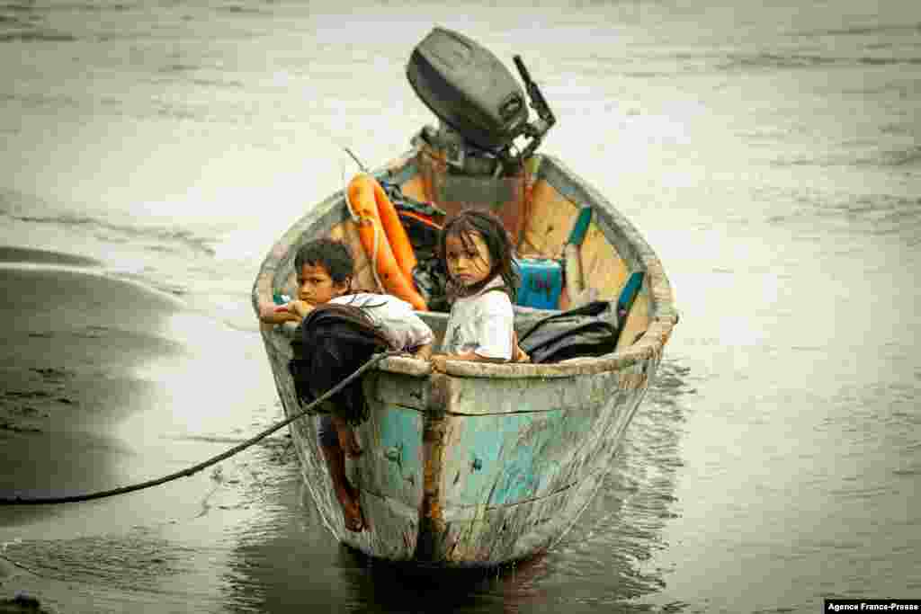 Children remain on a boat, after crude oil reached the Coca River in Puerto Maderos, Sucumbios province, Ecuador, Feb. 1, 2022. An oil spill caused by a ruptured pipeline in Ecuador's Amazon region leaked almost 6,300 barrels into an environmental reserve, according to the company that owns the conduit. 
