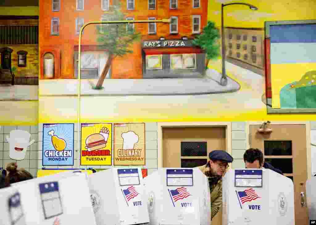 Peter McGough, left, talks with Adam Scheffer as they vote in a school cafeteria in New York, Nov. 8, 2016.
