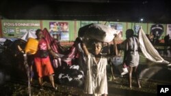 People affected by Saturday's earthquake recover their belongings under the rain of Tropical Depression Grace at a refugee camp in Les Cayes, Haiti, Aug. 16, 2021.