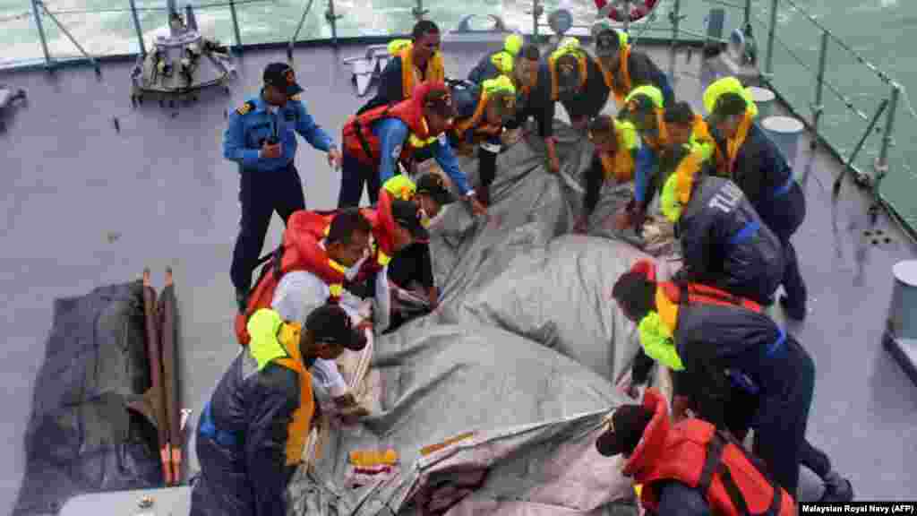 Royal Malaysian Navy crews retrieve the emergency evacuation tube from AirAsia Flight 8501 during their search-and-rescue operations in Indonesia's Java Sea.