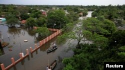 La gente viaja en botes en un área inundada después de que el río Paraná se desbordó debido a las fuertes lluvias, en Ayolas, Paraguay, 8 de noviembre de 2023.