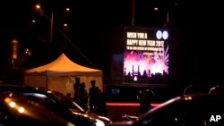 Indian policemen stand guard beside a display with new year message on New Year's eve in Hyderabad, India, Saturday, Dec. 31, 2016.