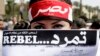 FILE - An Egyptian activist covers her face with an application for "Tamarod," Arabic for "rebel," a campaign calling for the ouster of Egyptian President Mohammed Morsi and for early presidential elections, during a protest in Tahrir Square, Cairo. 