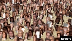 FILE - Multiple pictures of Baha'i religious leaders arrested in Iran are seen during a protest at Copacabana Beach in Rio de Janeiro, June 19, 2011.