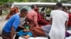 Medical workers and other Somalis help a civilian woman, who was wounded when a powerful car bomb blew off the security gates to the Elite Hotel, as she arrives at a hospital in Mogadishu, Somalia, Aug. 16, 2020. 