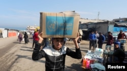 資料照片：在加沙中部的代爾巴拉赫地區，一名巴勒斯坦人頭頂聯合國近東巴勒斯坦難民救濟和工程處(UNRWA)分發的援助物品箱。 (2024年11月4日)