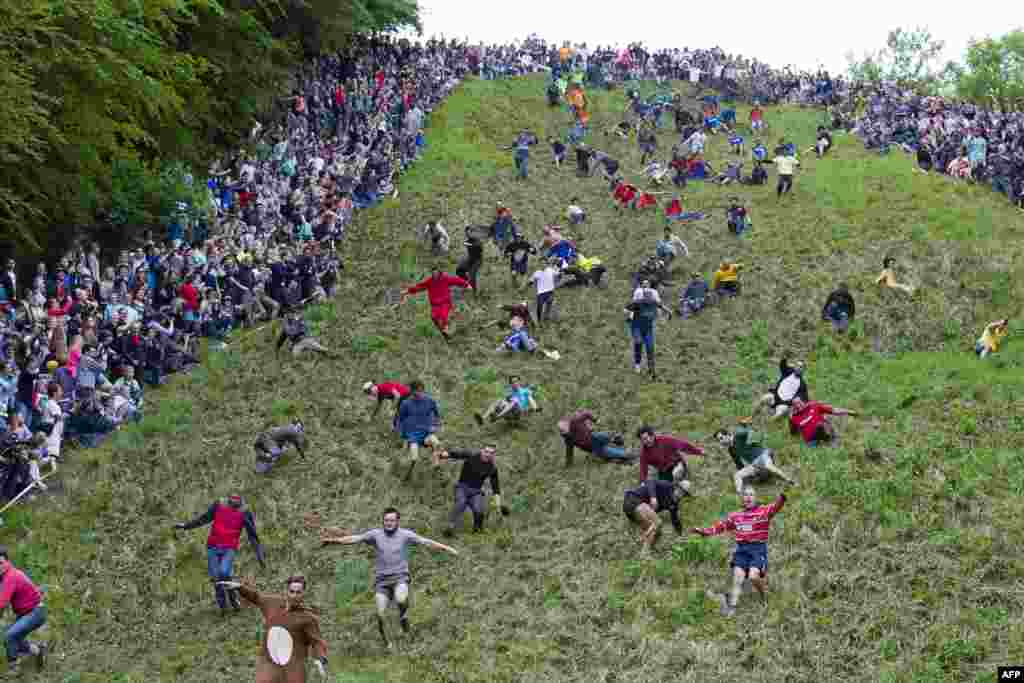 Competitors tumble down Coopers Hill in pursuit of a round Double Gloucester cheese during the annual cheese rolling and wake near the village of Brockworth near Gloucester in western England. With a disputed history dating back to at least the 1800s, the annual Cooper's Hill Cheese Rolling involves hordes of fearless competitors chasing an eight-pound Double Gloucester cheese down a steep hill.