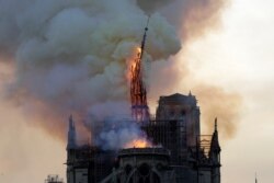 FILE - The steeple and spire of the landmark Notre-Dame Cathedral collapses as the cathedral is engulfed in flames in central Paris on April 15, 2019.
