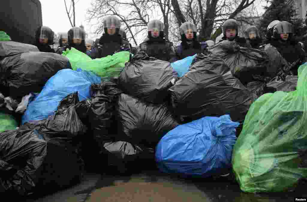 A pile of garbage bags left by pro-European integration protesters lies in front of riot police officers in Kyiv, Ukraine, Dec. 20, 2013.