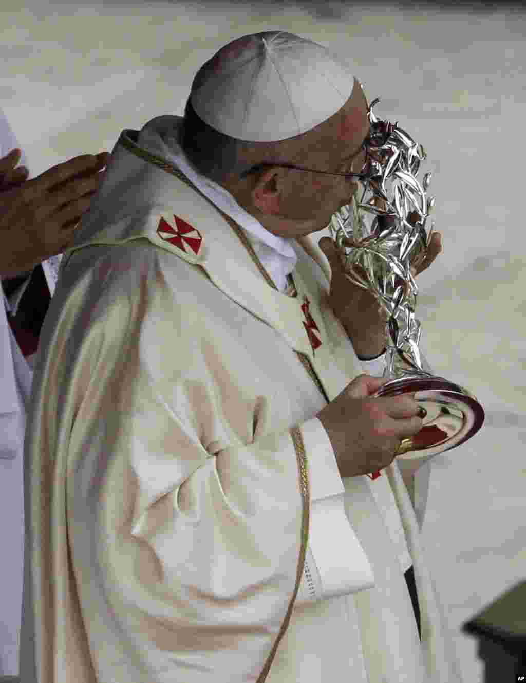 Pope Francis kisses a relic belonging to John Paul II during a ceremony in St. Peter's Square at the Vatican, April 27, 2014.
