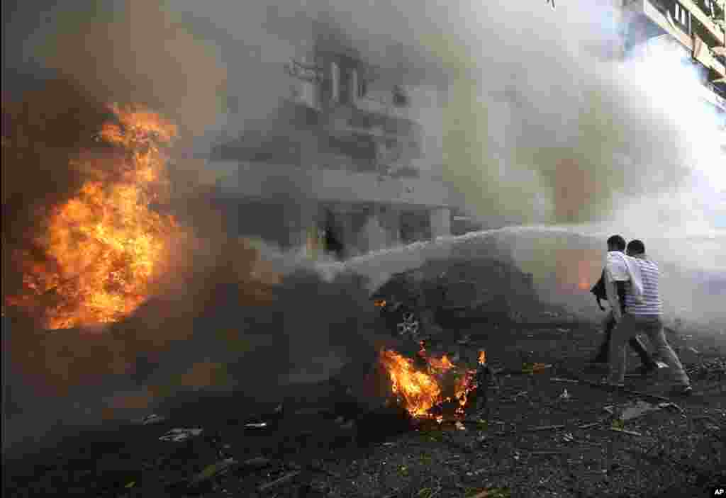 Two men react in front of burned cars after explosions near the Iranian embassy in Beirut, Nov. 19, 2013.