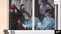 Medical staff perform a coronavirus test on a resident of a public housing unit during a spike in infections, in Melbourne, Australia, July 6, 2020. 