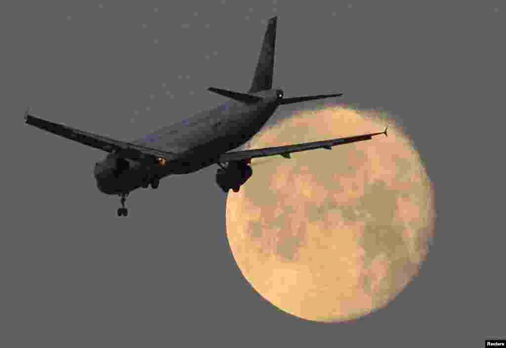 Sebuah pesawat penumpang saat akan mendarat di bandara Heathrow, London, pada malam bulan purnama.
