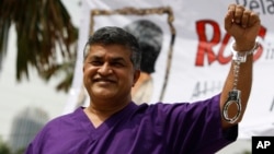 Kartunis Malaysia Zulkifli Anwar Alhaque, yang dikenal dengan nama Zunar, mengenakan seragam tahanan dan borgol plastik berpose bagi para fotografer dalam peluncuran bukunya di Petaling Jaya, Malaysia (14/2).