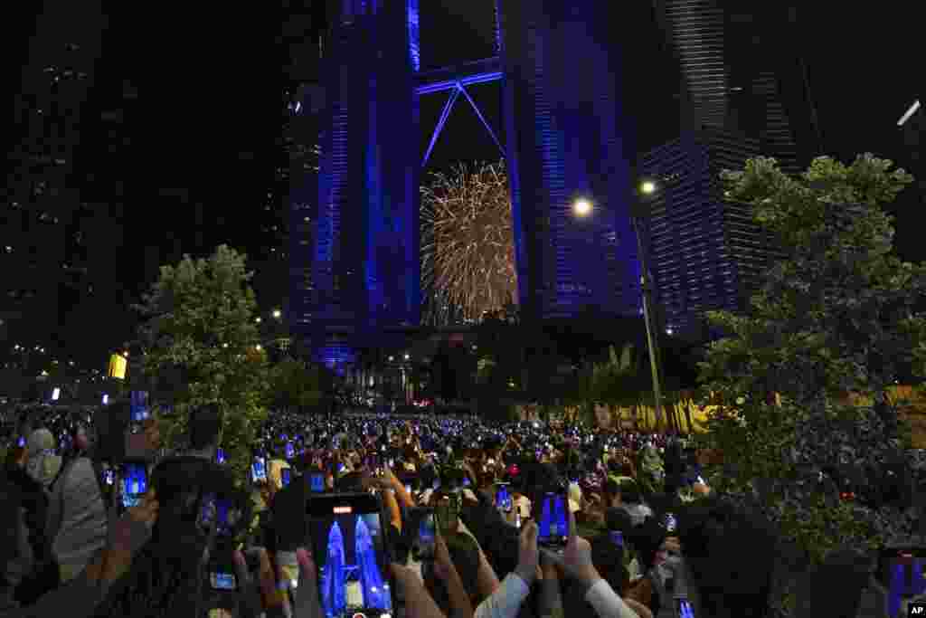 People take smartphones photos of the fireworks exploding near the Petronas Twin Towers, during the New Year's celebrations in Kuala Lumpur, Malaysia, Jan. 1, 2025.
