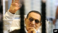 Former Egyptian President Hosni Mubarak waves to his supporters from behind bars as he attends a hearing in his retrial on appeal in Cairo, Egypt. (File photo)