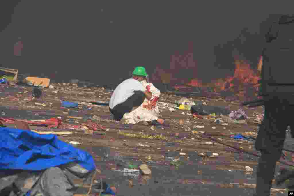 Seorang demonstran menolong korban terluka. (AP/Ahmed Gomaa)