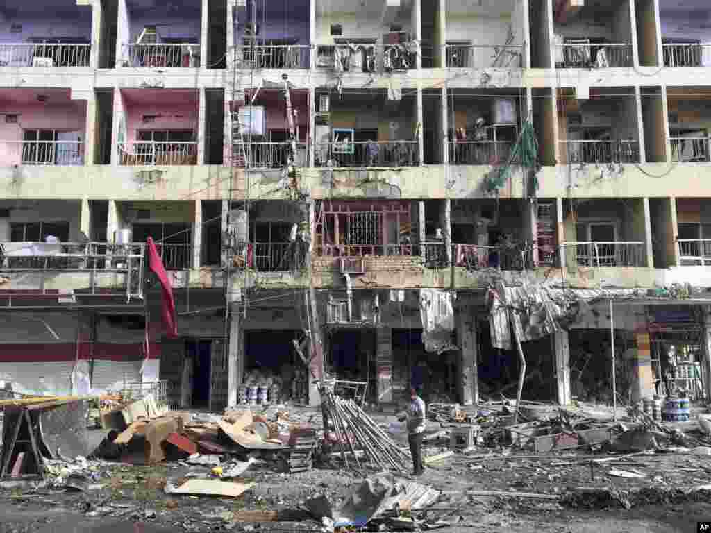 Iraqi civilians inspect the aftermath of a car bombing in the southeastern district of New Baghdad, Iraq, June 8, 2014.