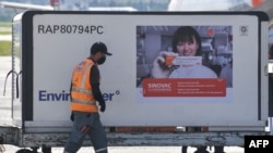 A worker is seen next to a container with dosees of the CoronaVac vaccine against COVID-19 unloaded from a cargo plane that arrived from China at Guarulhos International Airport in Guarulhos, Sao Paulo state, Brazil, on December 18, 2020.