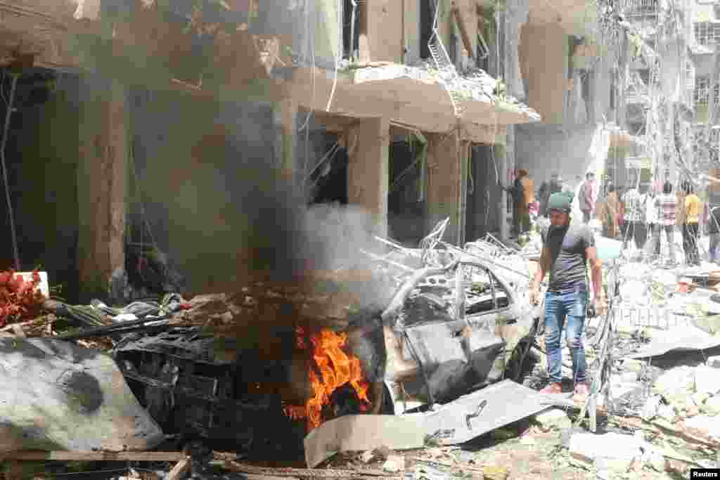People inspect the damage at a site hit by airstrikes in the rebel-held area of Aleppo's Bustan al-Qasr, April 28, 2016.