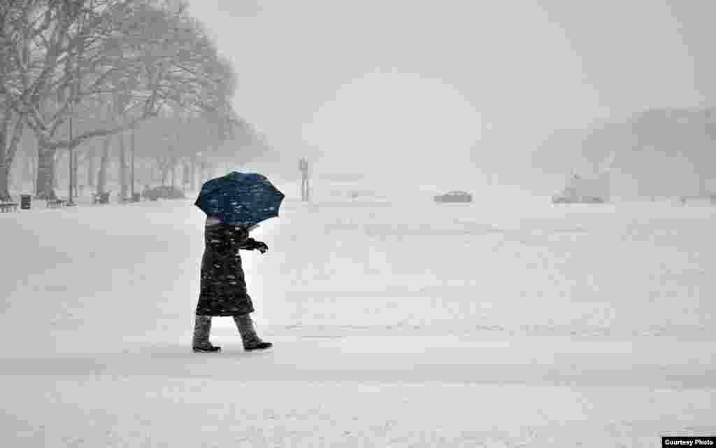 A pedestrian fights off the snow and wind with an umbrella during a winter storm in downtown Washington, D.C. (Photo taken by Dimitris Manis/VOA Greek Service)