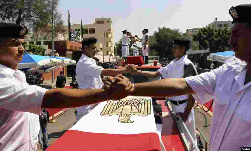 Police officers perform an honor guard during a funeral for colleagues killed during clashes in Cairo, August 15, 2013.
