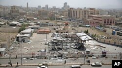 People stand in front of a petrol station after it was hit by Saudi-led airstrikes in Sana'a, Yemen, May 27, 2018.