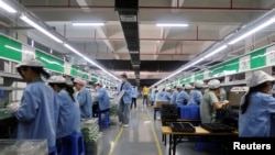 Sejumlah pekerja tampak sibuk bekerja pada lini produksi konsol mobile game RiotPWR di sebuah pabrik di Dongguan, Provinsi Guangdong, China, pada 7 Desember 2021. (Foto: Reuters/David Kirton)