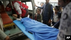 FILE - Yemenis carry the body of a girl who was killed in an explosion at a warehouse in Sanaa, April 7, 2019.