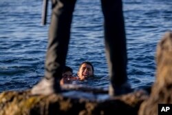 FILE - Penjaga sipil Spanyol menunggu para migran tiba di daerah kantong Spanyol di Ceuta, dekat perbatasan Maroko dan Spanyol, Rabu, 19 Mei 2021. (AP/Bernat Armangue)