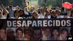 FILE - Women carry a banner calling attention to the cases of people who have gone missing in the fight against drug cartels and organized crime, demanding authorities locate their loved ones, May 10, 2018.