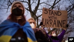 Seorang pria memegang poster yang berisi dukungan terhadap Ukraina dalam aksi protes menentang agresi Rusia di dekat Kedutaan Besar Rusia di Berlin, Jerman, pada 22 Februari 2022. (Foto: AP/Markus Schreiber)