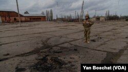 Un soldado ucraniano observa el lugar donde cayó una bomba que mató a otro soldado no lejos de la línea del frente en el este de Ucrania, el 19 de febrero de 2022, en Novoluganske, Ucrania. (Yan Boechat/VOA)