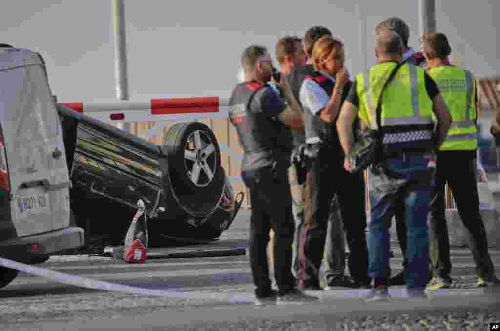 Police officers speak near an overturned car at the spot where terrorists were intercepted by police in Cambrils, Spain, Aug. 18, 2017. 