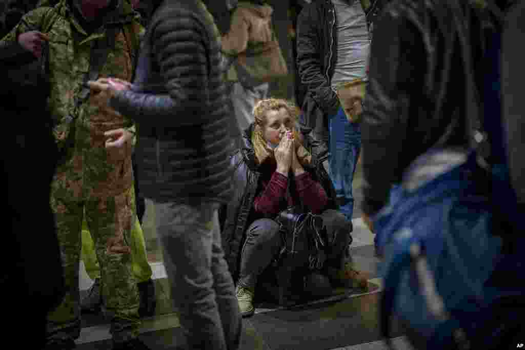 A woman reacts as she waits for a train trying to leave Kyiv, Ukraine, after Russian troops launched their anticipated attack on the country.