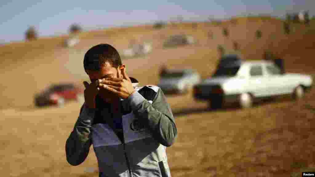 A man wipes his eyes after Turkish military fired tear gas in an attempt to clear a hill of observers, near the Mursitpinar crossing on the Turkish-Syrian border, Oct. 26, 2014.