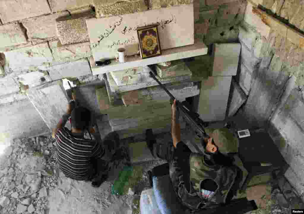 Members of the Free Syrian Army aim their weapons as they take up a defensive position in Aleppo's Salaheddine district, Syria, June 25, 2013.