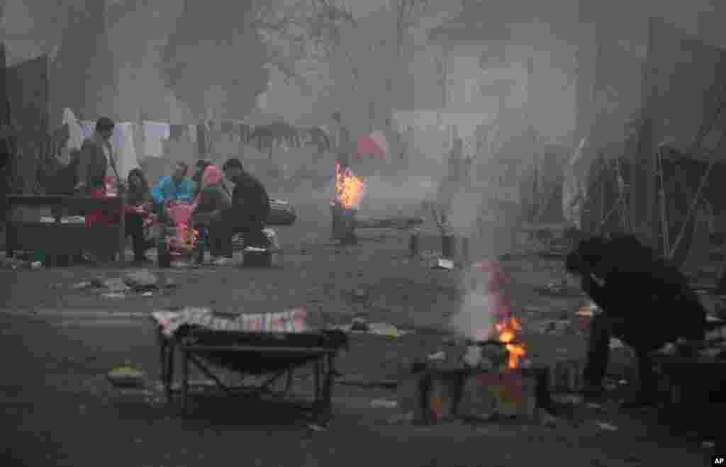 Pengungsi Suriah menghangatkan diri dekan api di depan tenda mereka di kamp pengungsian di kota Harmanli, Bulgaria, Kamis, 21 November 2013.