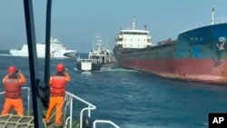 Kapal-kapal Penjaga Pantai Taiwan bersiap untuk menaiki kapal kargo berbendera Togo, Hongtai, yang diduga telah memutus kabel komunikasi bawah laut di perairan antara pantai barat pulau utamanya dan Kepulauan Penghu, 25 Februari 2025. (Penjaga Pantai Taiwan via AP)