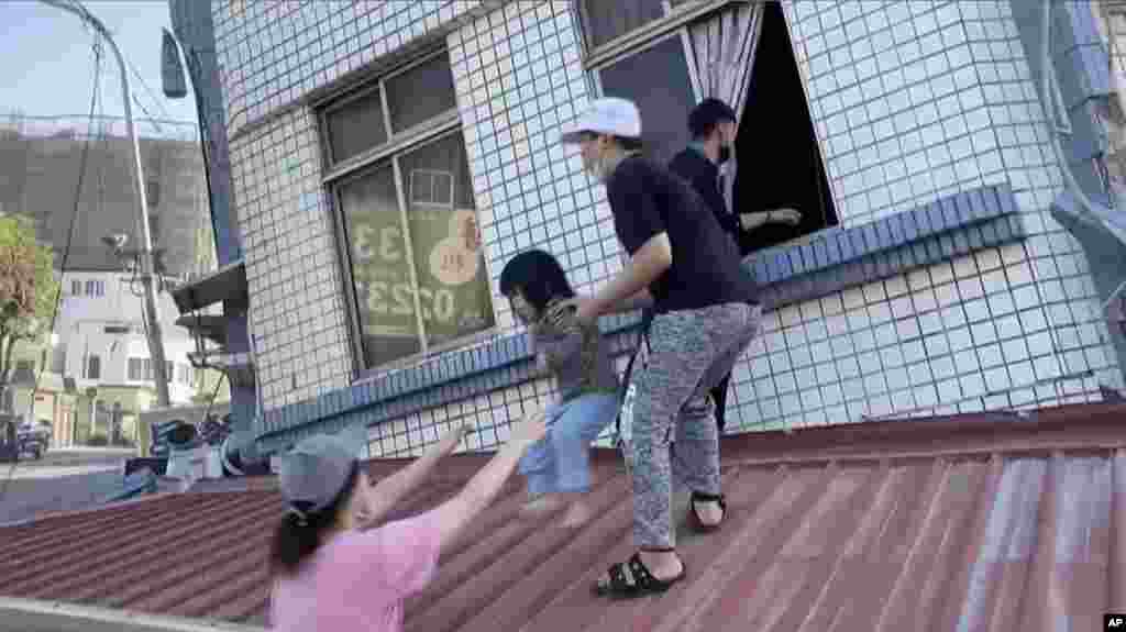 In this image taken from a video footage run by TVBS, residents rescue a child from a partially collapsed building in Hualien, eastern Taiwan, April 3, 2024.