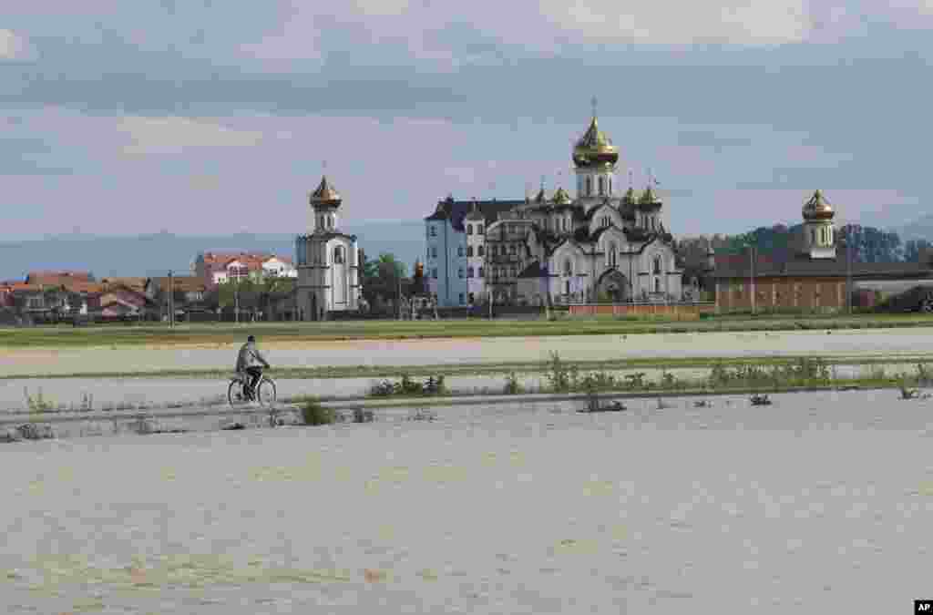 A man drives his bicycle away from a flooded area in the village of Dvorovi, near Bijeljina, Bosnia-Herzegovina, May 17, 2014.