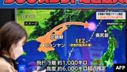 FILE - Seorang pejalan kaki berjalan melewati layar televisi yang menayangkan laporan berita tentang peluncuran rudal Korea Utara, di Tokyo, 18 Desember 2023.