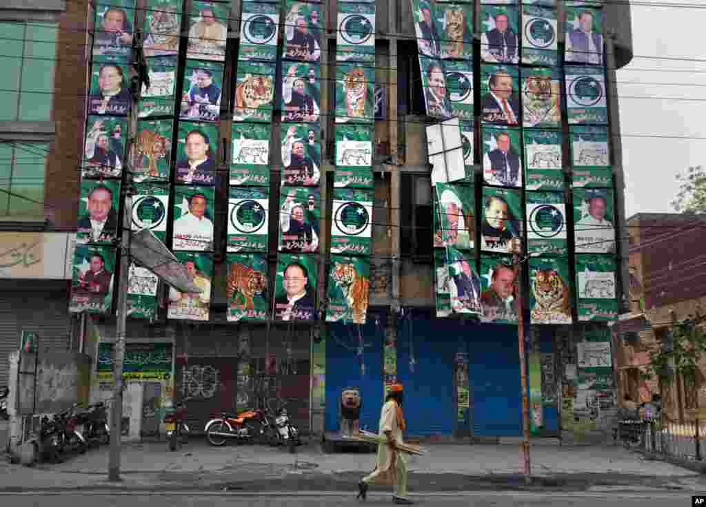A man walks past posters of former prime minister and Pakistan Muslim League party chief Nawaz Sharif, displayed on his party's office building in Lahore, May 12, 2013.