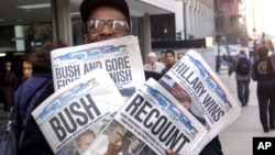 Foto del 8 de noviembre de 2000 en donde Willie Smith muestra cuatro copias del Chicago Sun-Times, cada una con cuatro titulares diferentes que van desde recuento hasta anunciar el triunfo de Bush y el de Al Gore.
