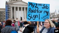 Melissa Knight, who teaches art at Ardmore, Oklahoma, middle school, holds a sign as teachers rally against low school funding at the state Capitol in Oklahoma City, April 2, 2018.