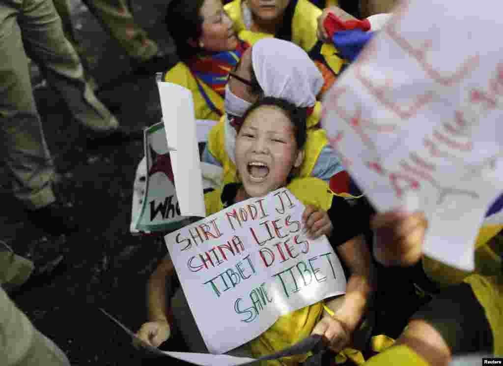 Tibetan exiles shout slogans as they struggle with police during a protest while Chinese President Xi Jinping and Indian Prime Minister Narendra Modi hold a meeting, in New Delhi, Sept. 18, 2014.