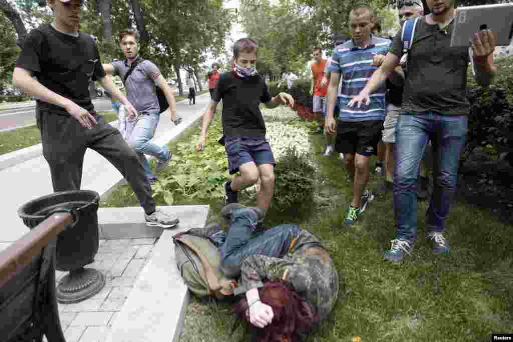 Beberapa pemuda menendang seorang aktivis hak-hak gay selama protes terhadap RUU anti-gay di pusat kota Moskow, Rusia.
