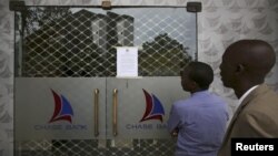 People read a notice from the Central Bank of Kenya taped to the closed entrance of a Chase Bank branch, after the bank was put under receivership, in Nairobi, April 8, 2016.